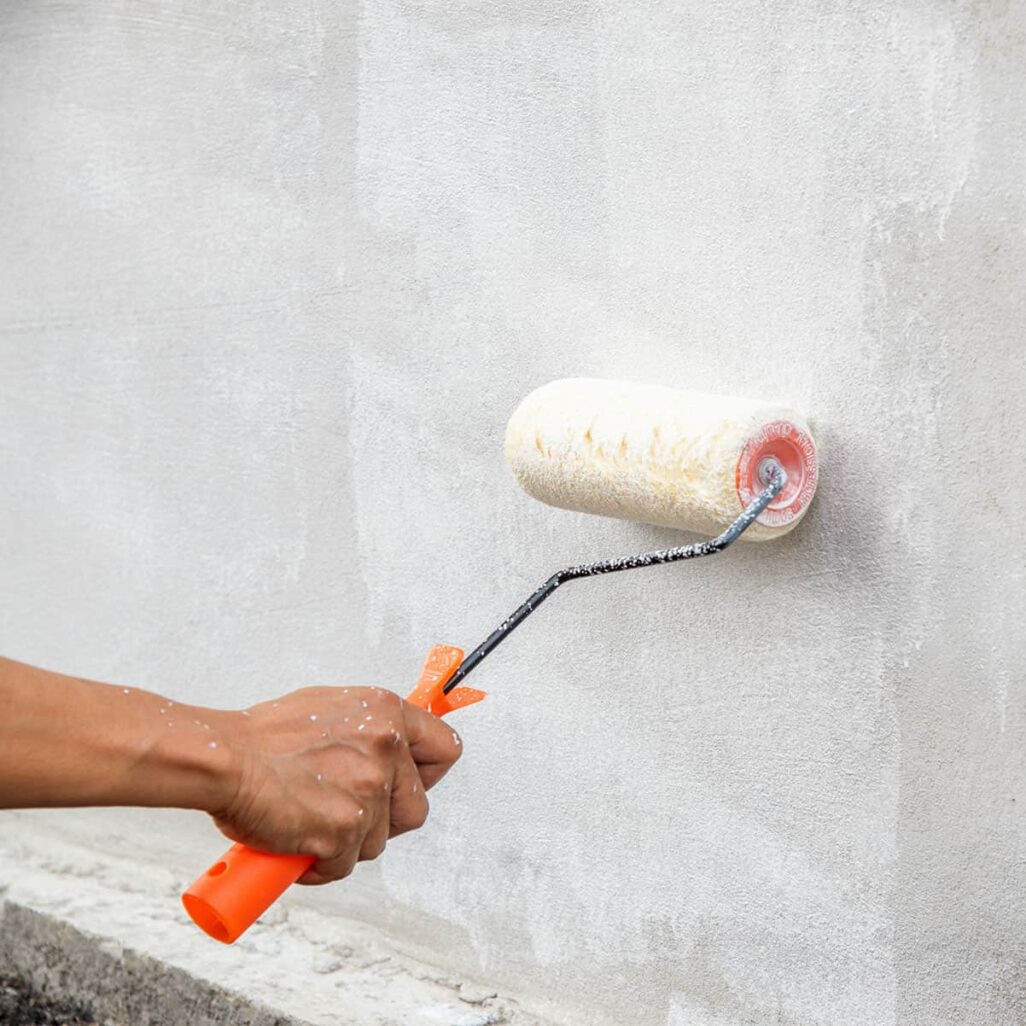 Personne appliquant de la peinture blanche sur un mur elle-même, méthode DIY non recommandée par HUMY