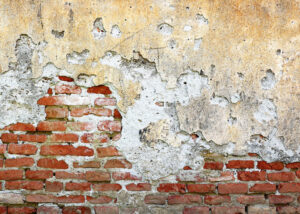 mur en briques avec couche de plâtre craquelée à cause de l’humidité
